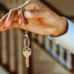 A close-up shot of a hand holding a house key, indicating new ownership or rental