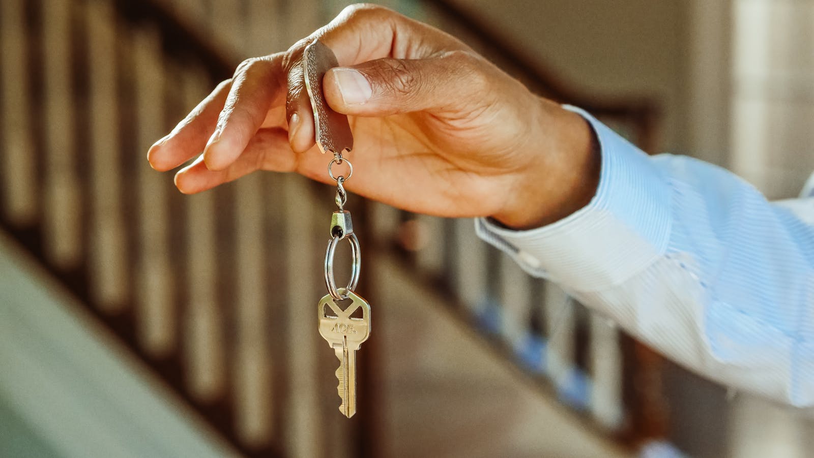 A close-up shot of a hand holding a house key, indicating new ownership or rental