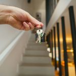 Here's a possible caption: keys being held in front of a staircase
